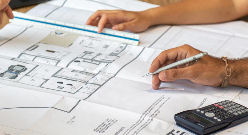 paper building plans with calculator, ruler and pencil